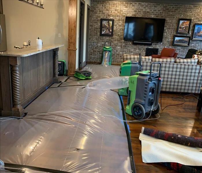 Drying chambers on hardwood floors connected to SERVPRO dehumidifiers with nearby air movers