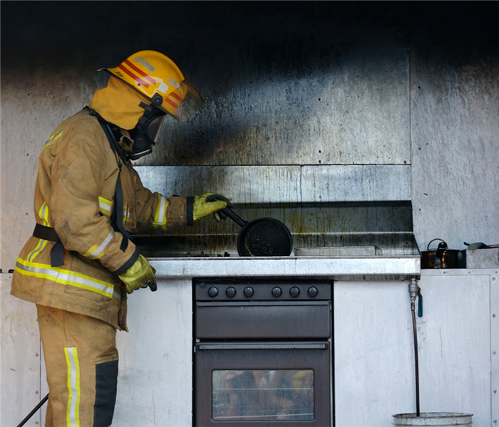 a fireman taking a pot off of a burned stovetop
