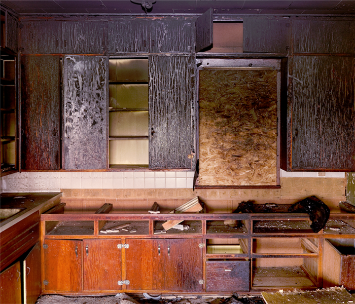 a fire damaged kitchen with soot covering the walls and cabinets
